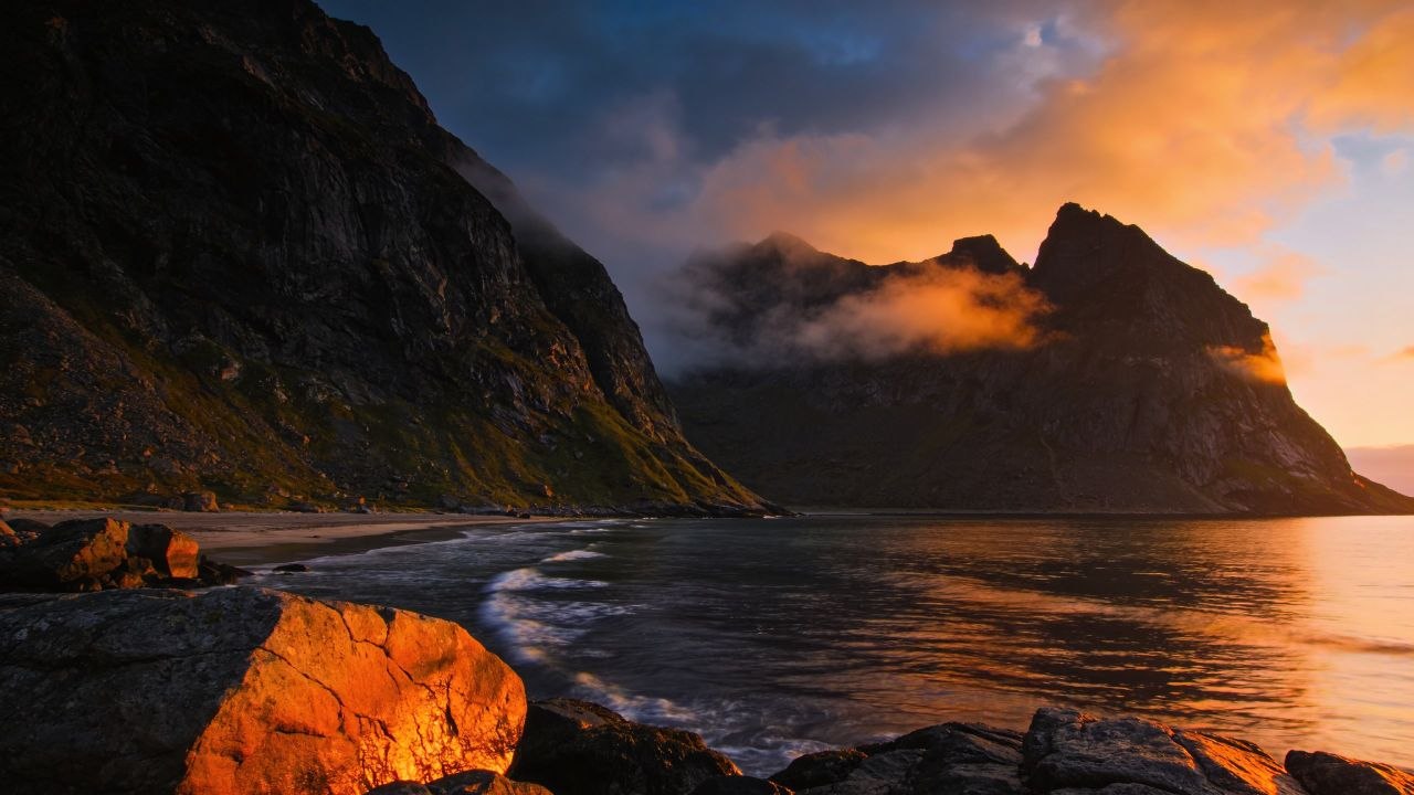 Coastal landscape at golden hour — mountains, water and rocks